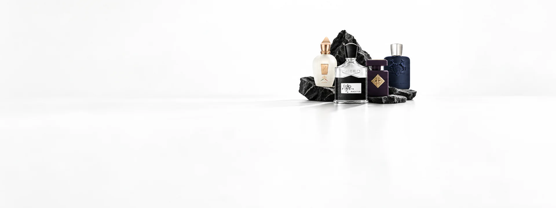 Xerjoff, Creed Aventus, Initio and Parfums de Marly bottles on dark stone